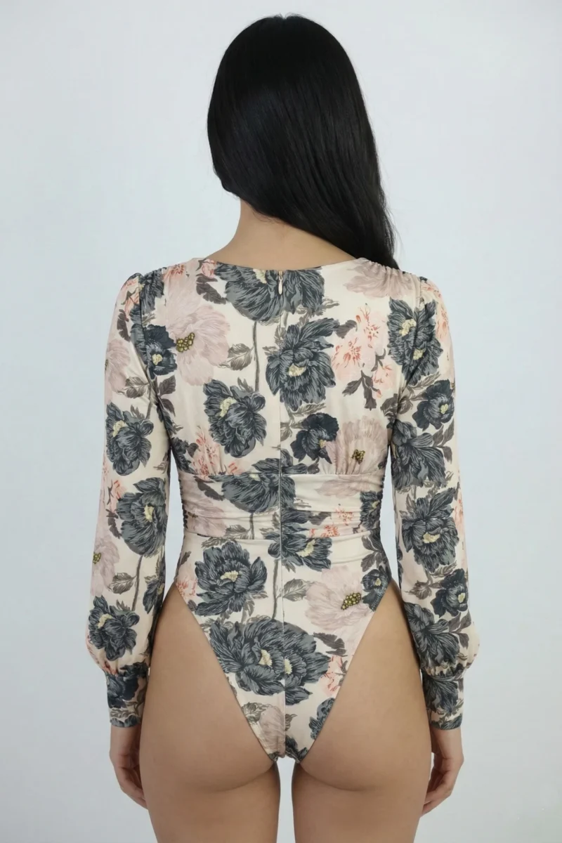 Body damskie w kwiaty w eleganckim dominującym beżowym kolorze, dekolt w serek i długie rękawy z marszczeniami przy ramionach.