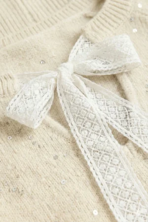 Sweter damski ecru w luźnym fasonie z okrągłym dekoltem, długimi rękawami i ściągaczami na mankietach.