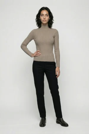 Elegancka kobieta w beżowym półgolfie i czarnych spodniach