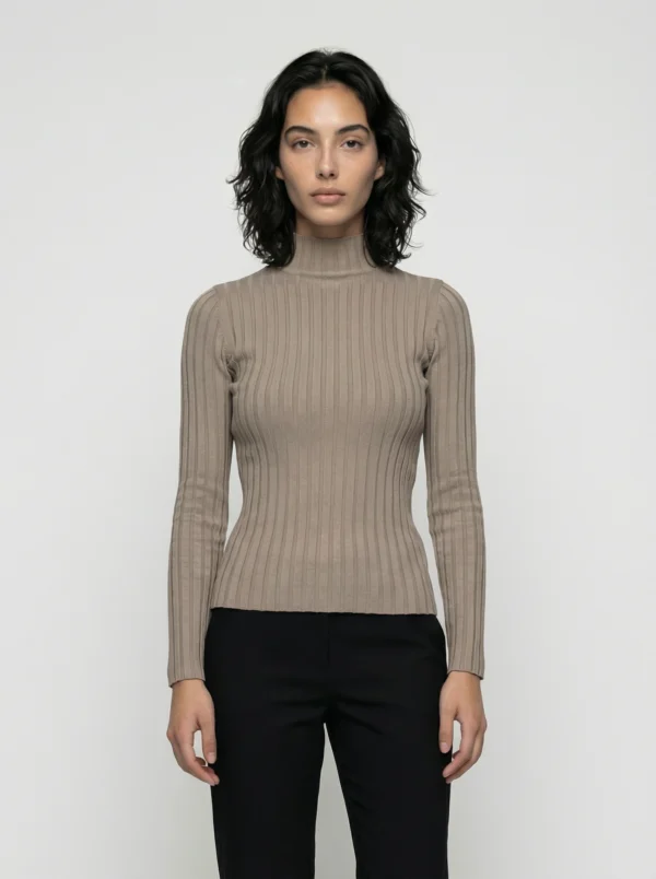 Kobieta w beżowym golfie i czarnych spodniach na białym tle