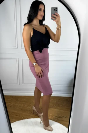 Kobieta w różowej spódnicy midi robi selfie.