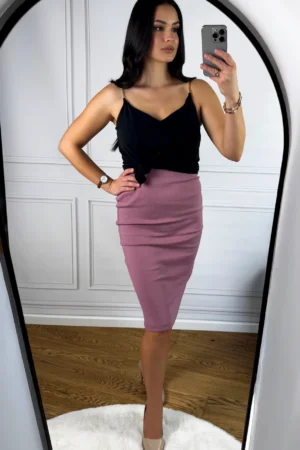 Kobieta w czarnym topie i różowej spódnicy midi z prążkowaną fakturą